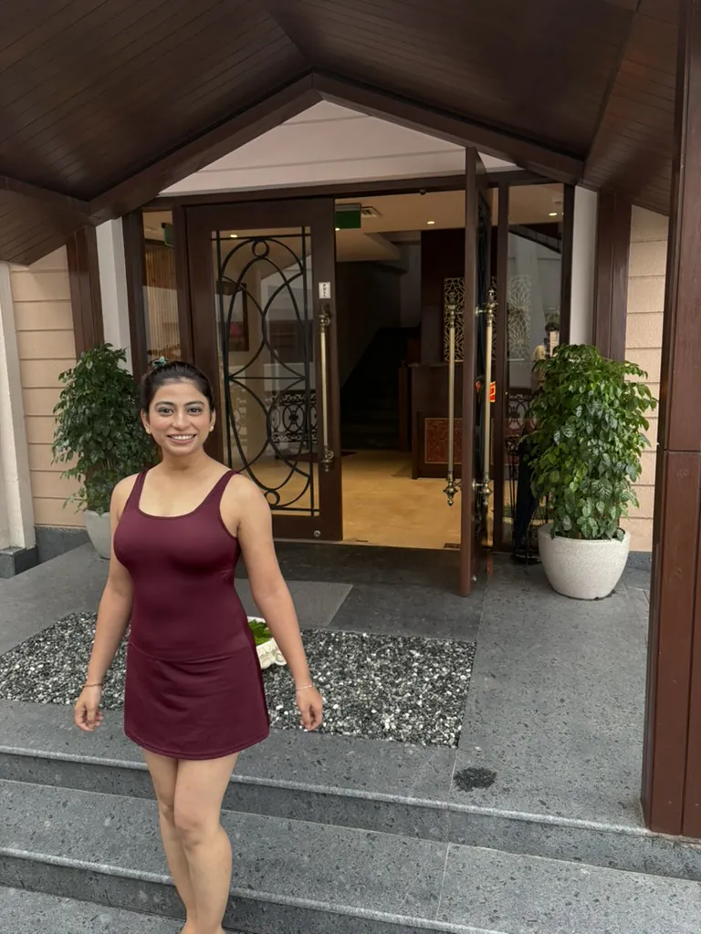 Divya smiling at the hotel entrance in a burgundy dress